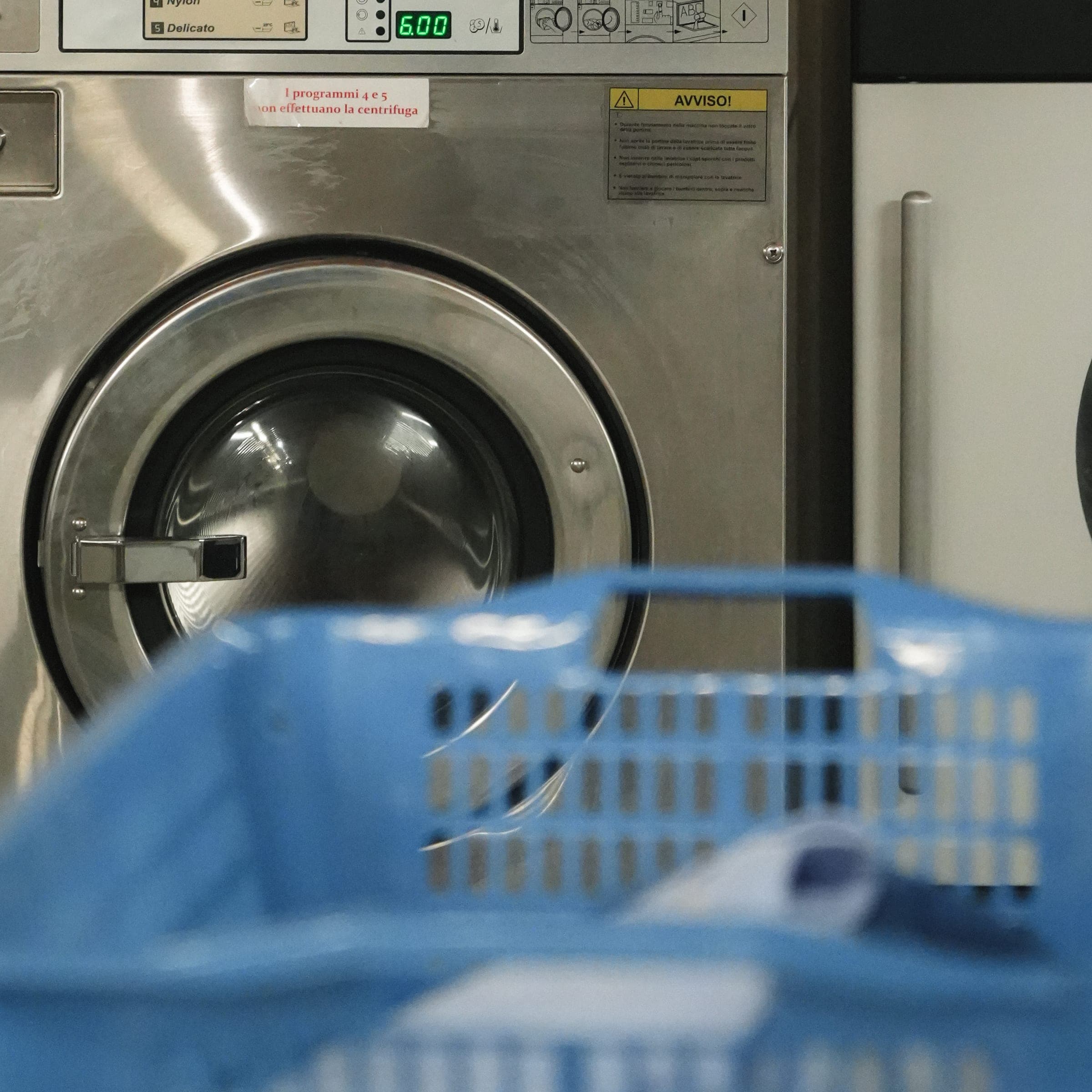 Un cesto azzurro per il bucato davanti alle lavatrici Maytag del negozio