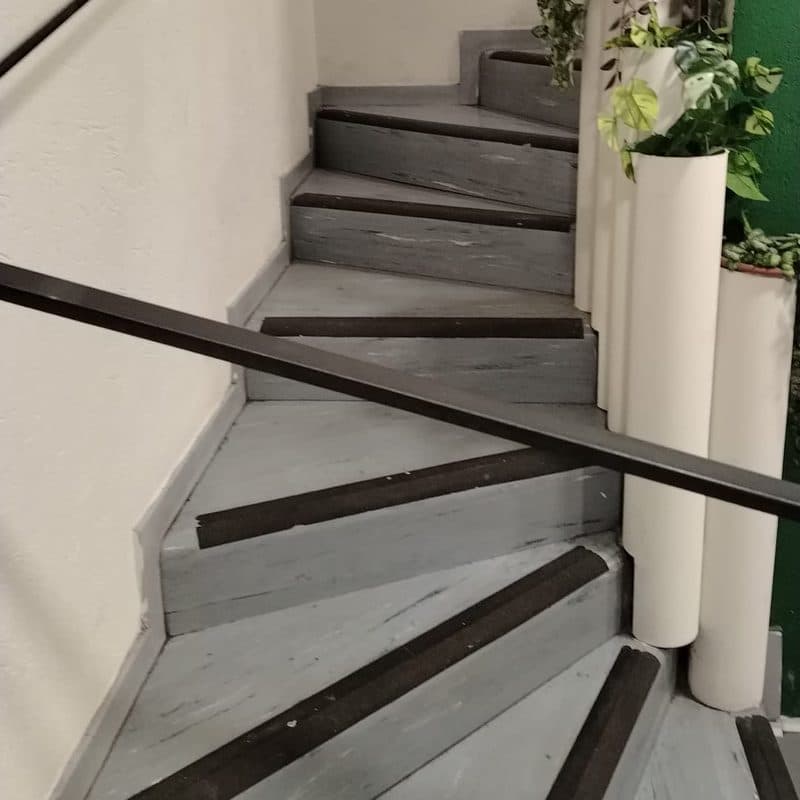 The stairs down to the laundry, with a handrail and non-slip strips on the steps